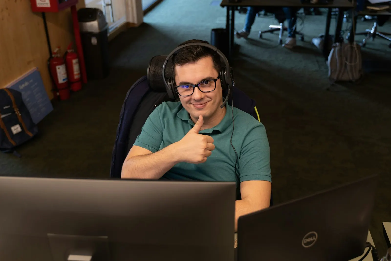 Técnico de soporte sonriente con audífonos frente al computador