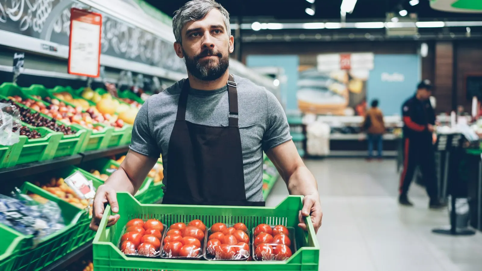 Almacenero con una caja de tomates en su local